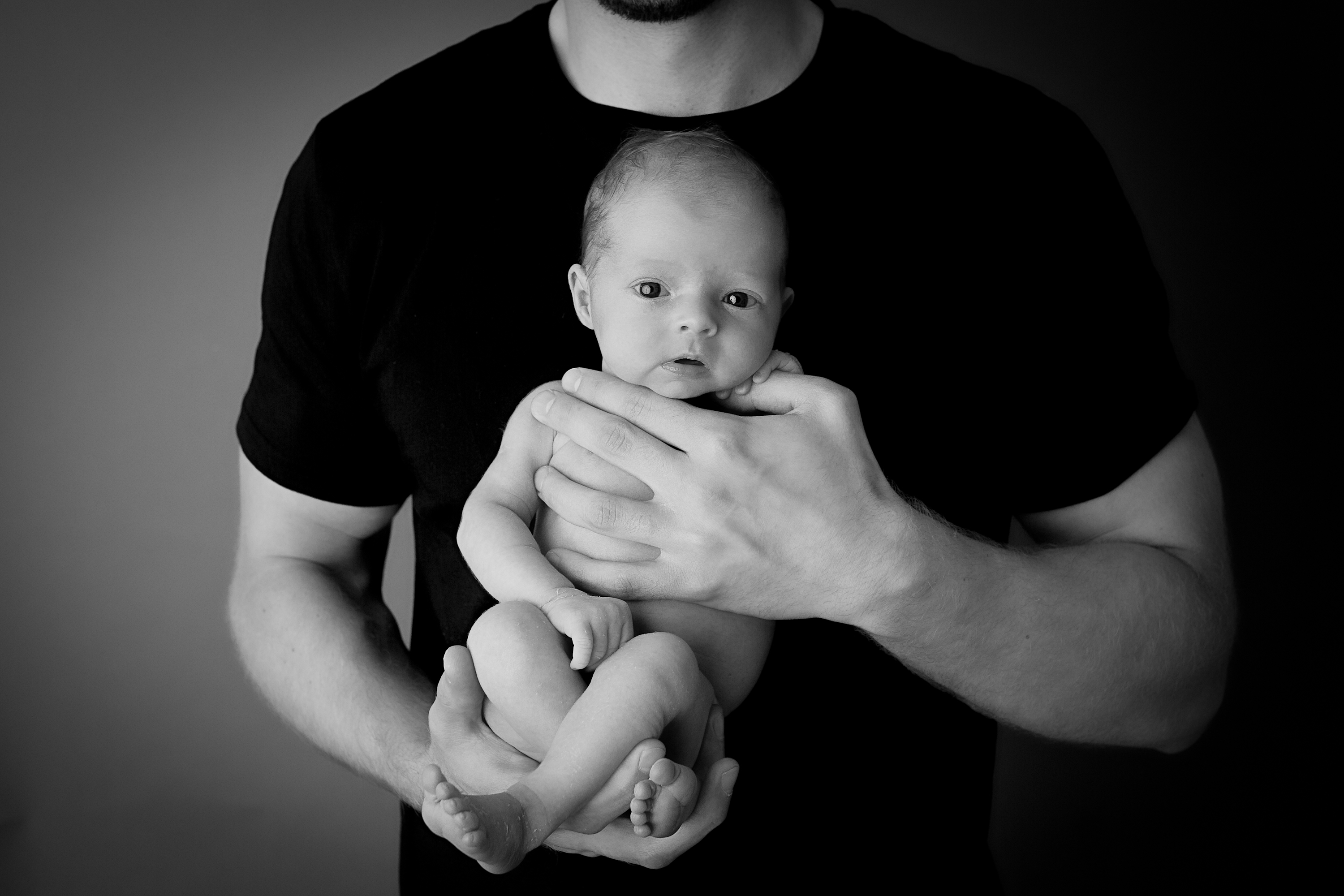 Dad holding awake newborn Photograph - Baby Whispers Photography Royston Cambridgeshire