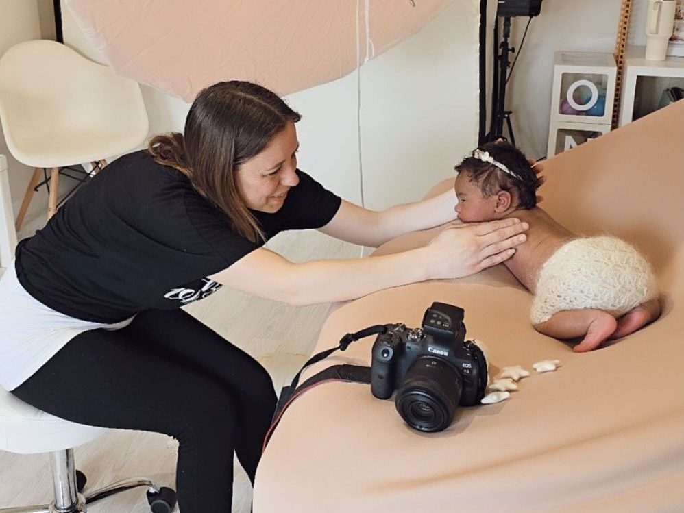 behind the scenes at a newborn photoshoot Photographer posing sleeping baby at studio in Royston.