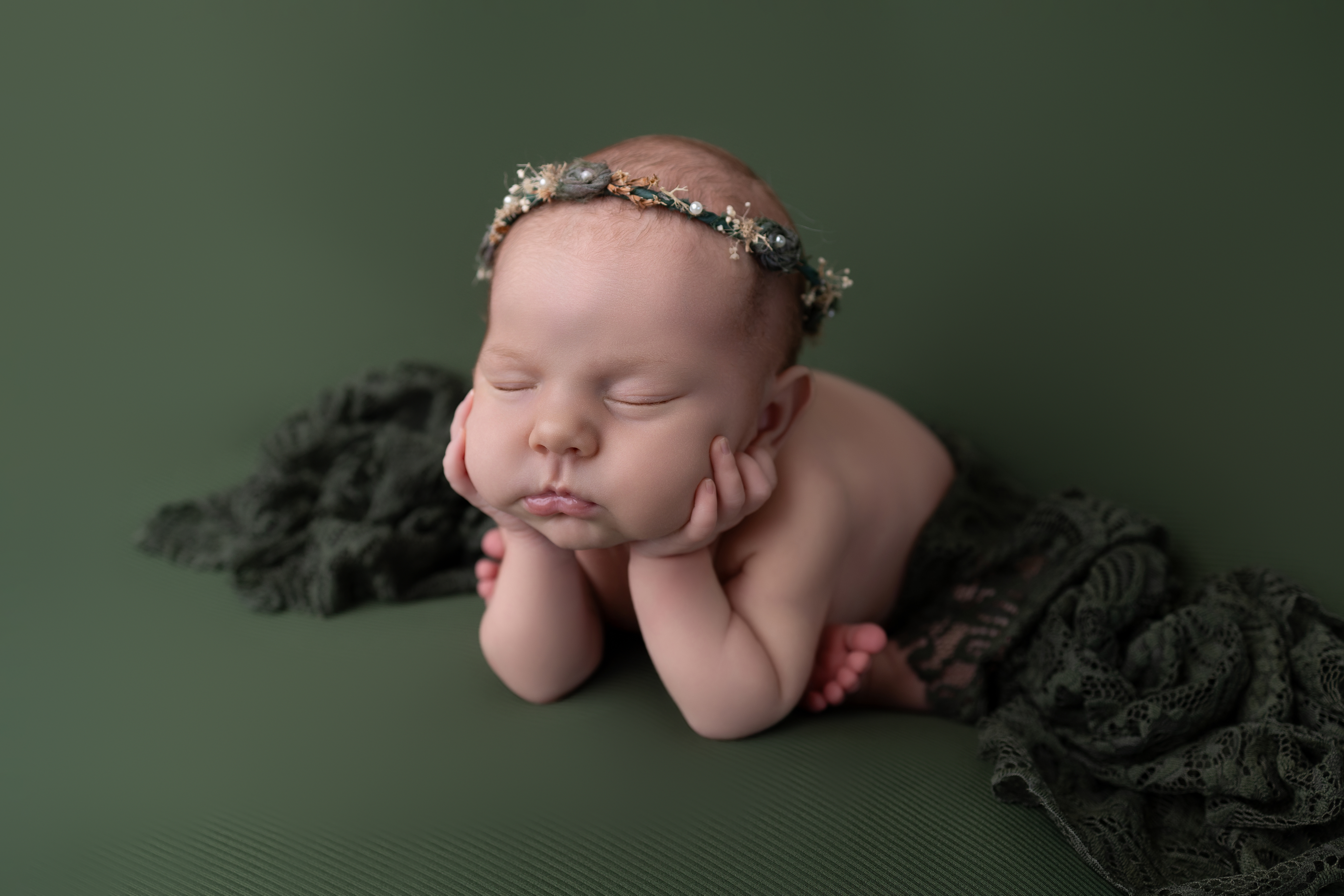 Sleeping posed newborn baby photographed in newborn studio in Royston, Hertfordshire posed froggy pose on emerald green backdrop