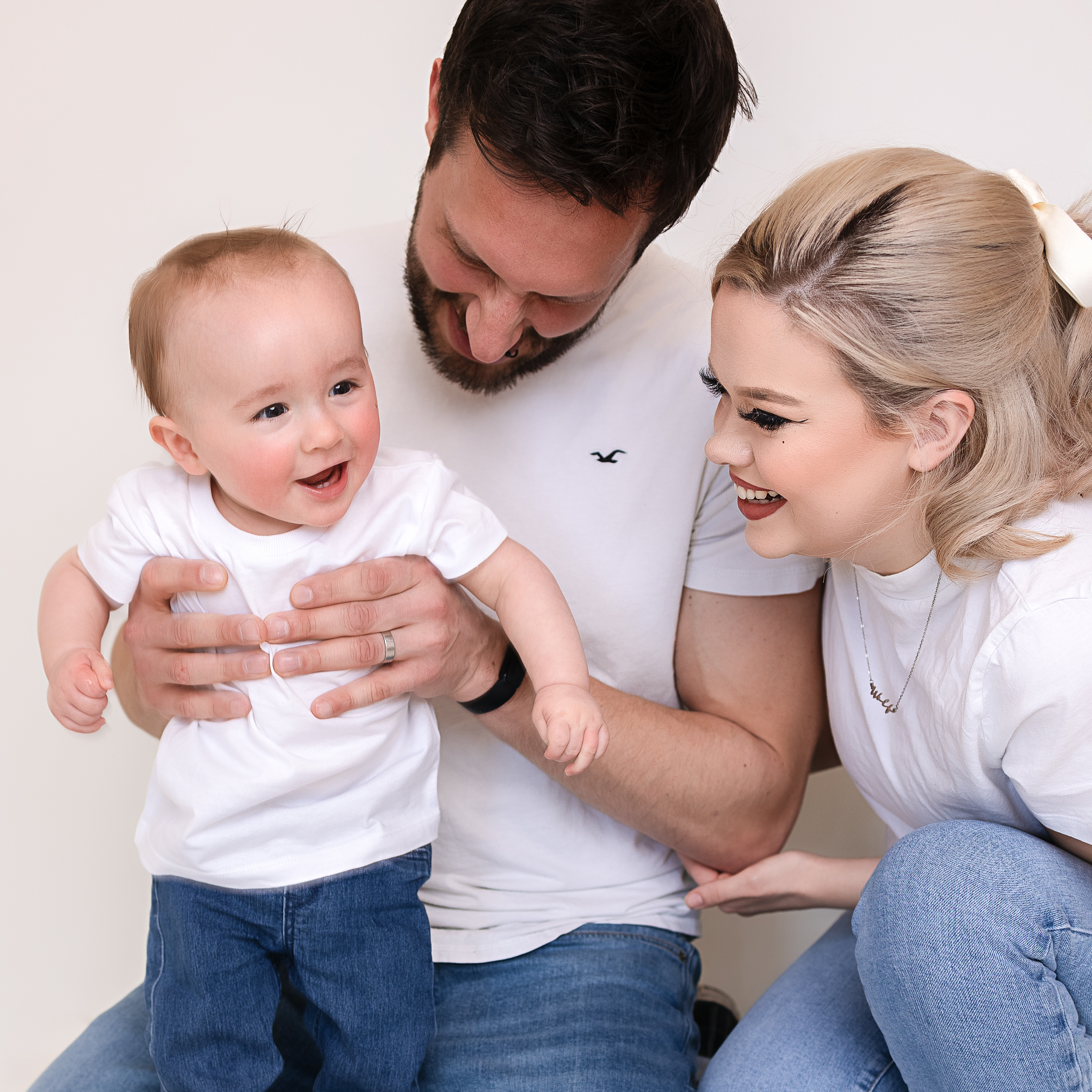 baby boy laughing with his parents watching and smiling with him